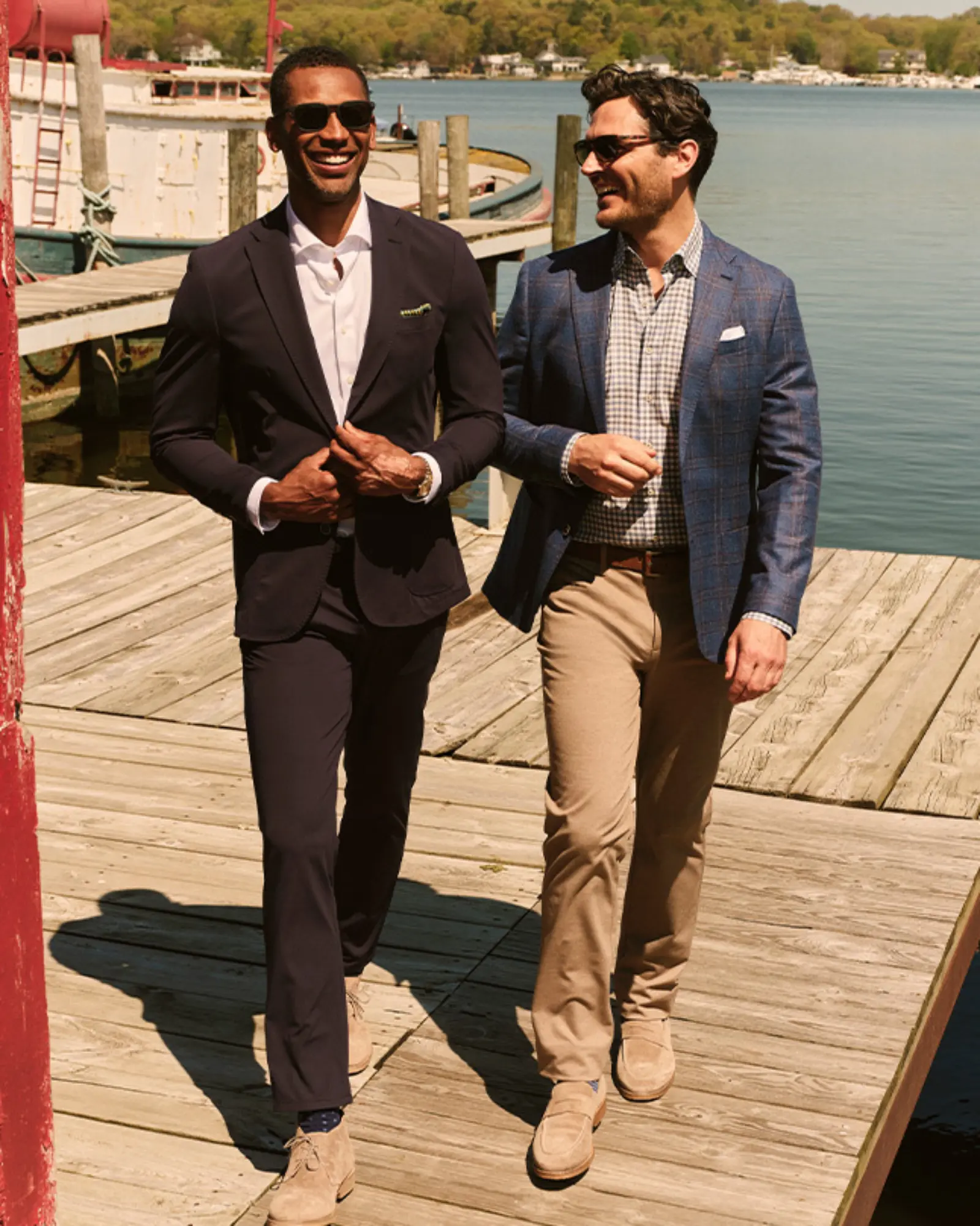 Two men dressed in blazers and nice pants walking down a dock
